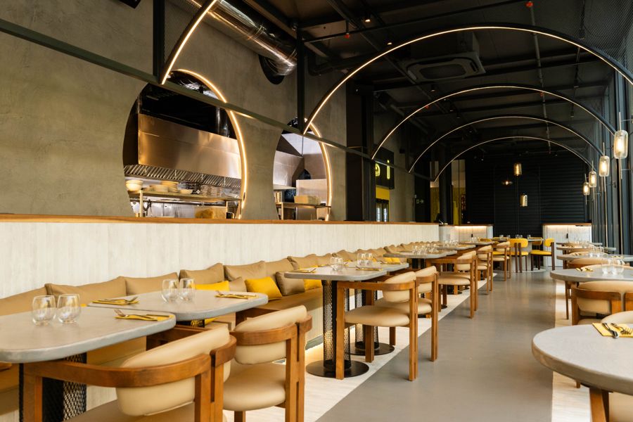 Sala de Dedos La Gran Manzana con arcos de luz, bancos corridos y cocina vista